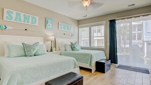 Une chambre avec deux lits, une fenêtre avec des stores et une vue sur l’extérieur.
