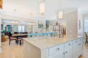 A spacious kitchen with a large island, pendant lighting, and a view of the dining area. - Ocean-View Escape  — Steps to the Beach! (Myrtle Beach)