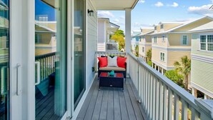 Un balcon avec un canapé et des coussins, une balustrade et une vue sur les maisons voisines.