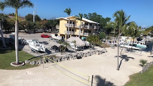 Un hotel frente a la playa con varios balcones, una playa de arena y varios barcos amarrados cerca.