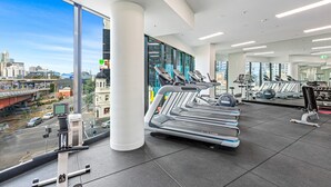 A modern gym with treadmills, weights, and a city view. - Pristine 2-Bed Unit With Beautiful City Landscape (Southbank)