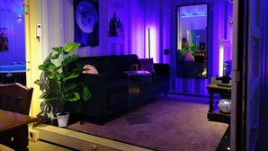 A living room with a sofa, a potted plant, a mirror, and a poster on the wall.