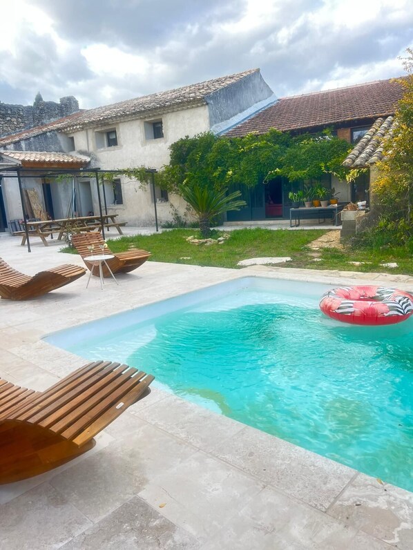 A swimming pool with wooden loungers and a red inflatable ring.