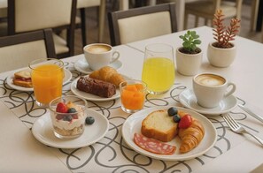 A breakfast setting with croissants, a sandwich, a dessert, coffee, and juice on a table. - La Tana del Furlo (Cagli)