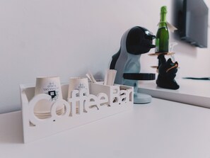 Ein Kaffee-Bereich mit Kaffeemaschine, einer Champagnerflasche und einer dekorativen Katzenfigur.