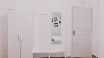 Ein Zimmer mit Schrank, Sitzbank, Spiegel und Tür.