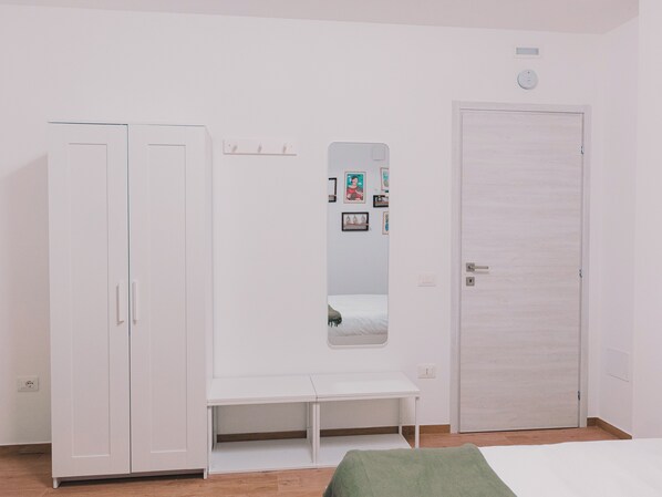 Una habitación con armario, banca, espejo y puerta.