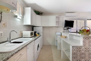 A compact kitchen with a sink, microwave, and washing machine. - Apartment with Shared Pool, Wi-Fi and Air Conditioning (Albufeira)