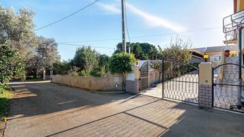 A residential street with a gated entrance, a basketball hoop, and a clear sky.