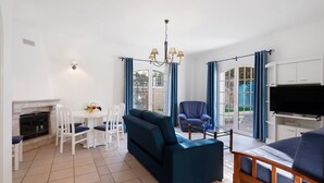 A living room with a sofa, chairs, a TV, and a fireplace. - Holiday Home with Shared Pool (Albufeira)