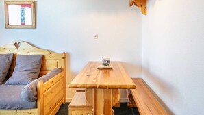 A wooden bed with a heart-shaped headboard, a wooden table with benches, and a framed picture on the wall. - Mountain hideaway in Risoul (Risoul)