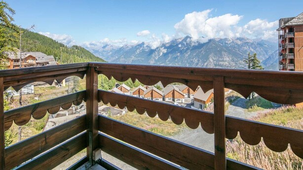 A wooden balcony with a view of mountains and a village below. - Mountain hideaway in Risoul (Risoul)