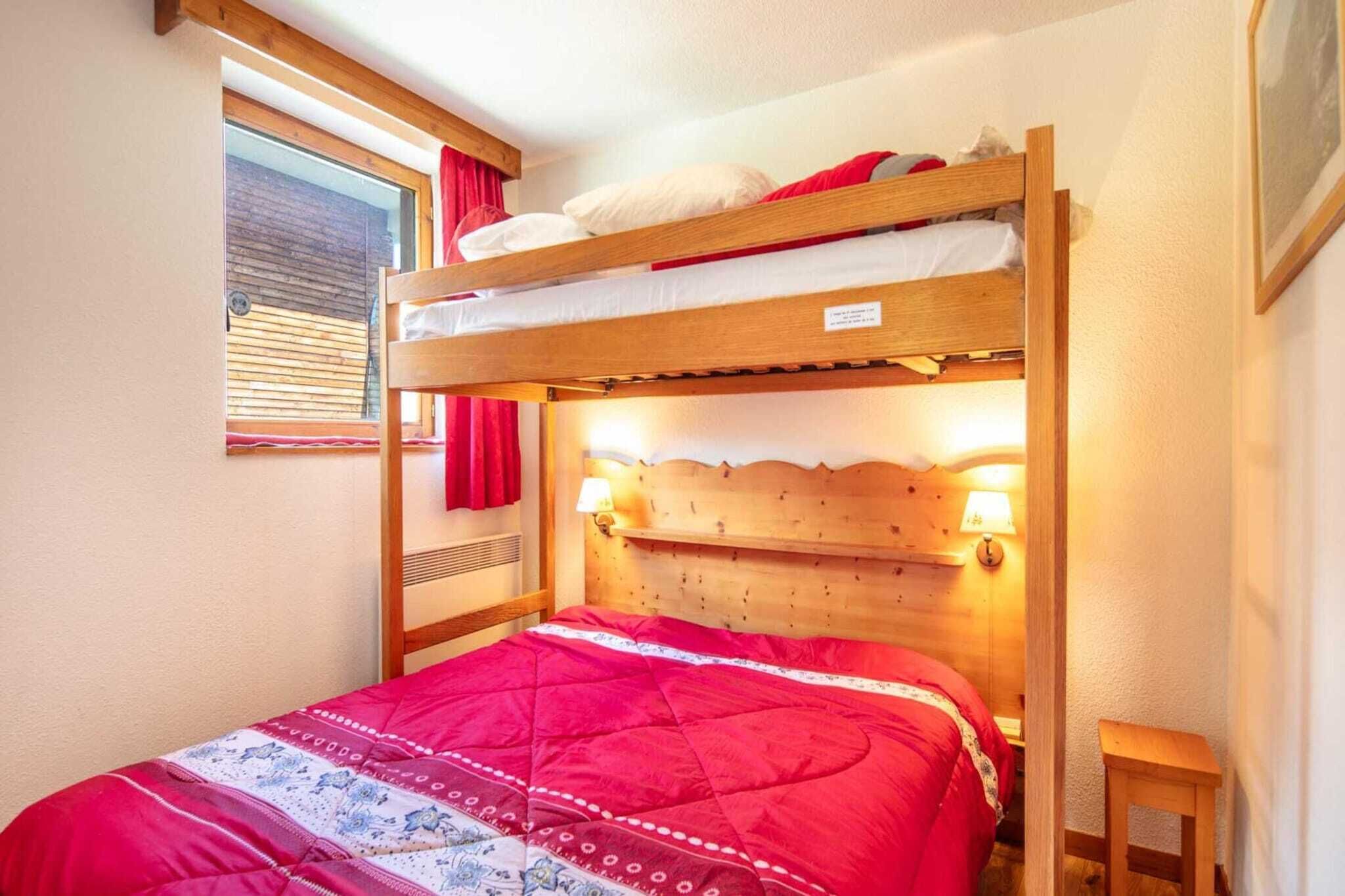 Een stapelbed met een rode sprei en twee bedlampjes.