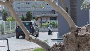 En parkeringsplats med en bil och en motorcykel, omgiven av ett staket och träd.