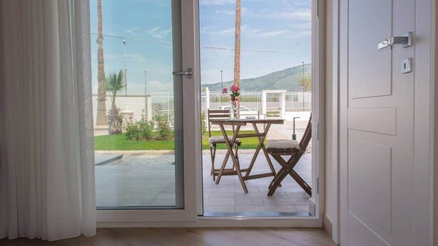 Una habitación con puerta de vidrio corredera que da a un patio exterior con mesa y sillas.