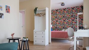Una habitación con cama, escritorio, silla, armario y una pequeña mesa con plantas.