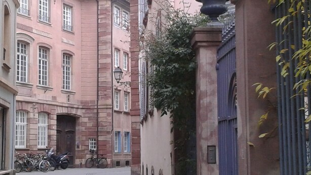Un carrer estret amb edificis històrics, una porta blava i bicicletes aparcades al costat.