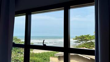 A window with a view of the ocean and greenery.