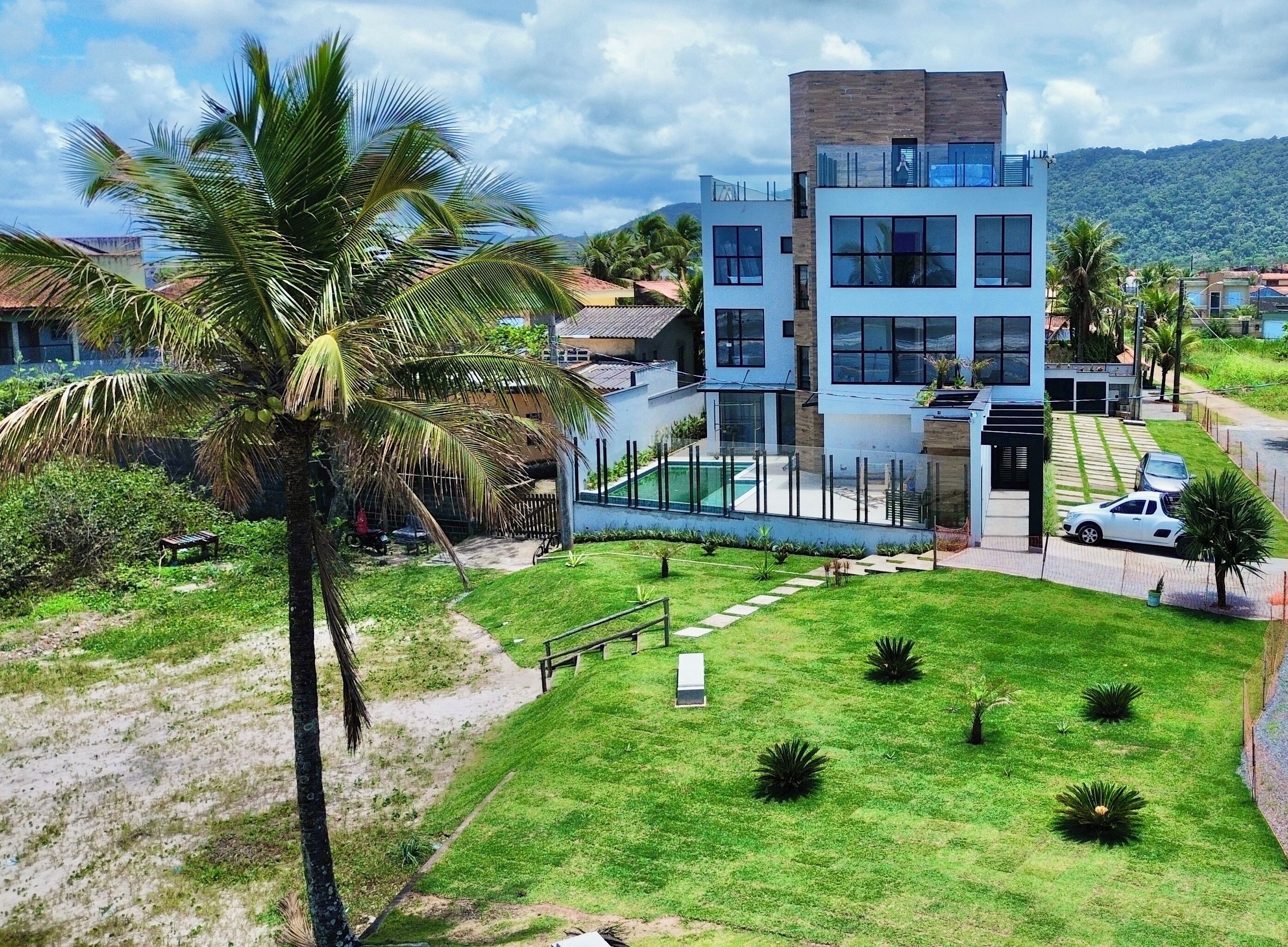 A modern two-story building with a swimming pool, surrounded by well-maintained lawns and palm trees.