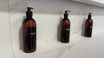 Three brown bottles with black pumps on a white tiled shelf.