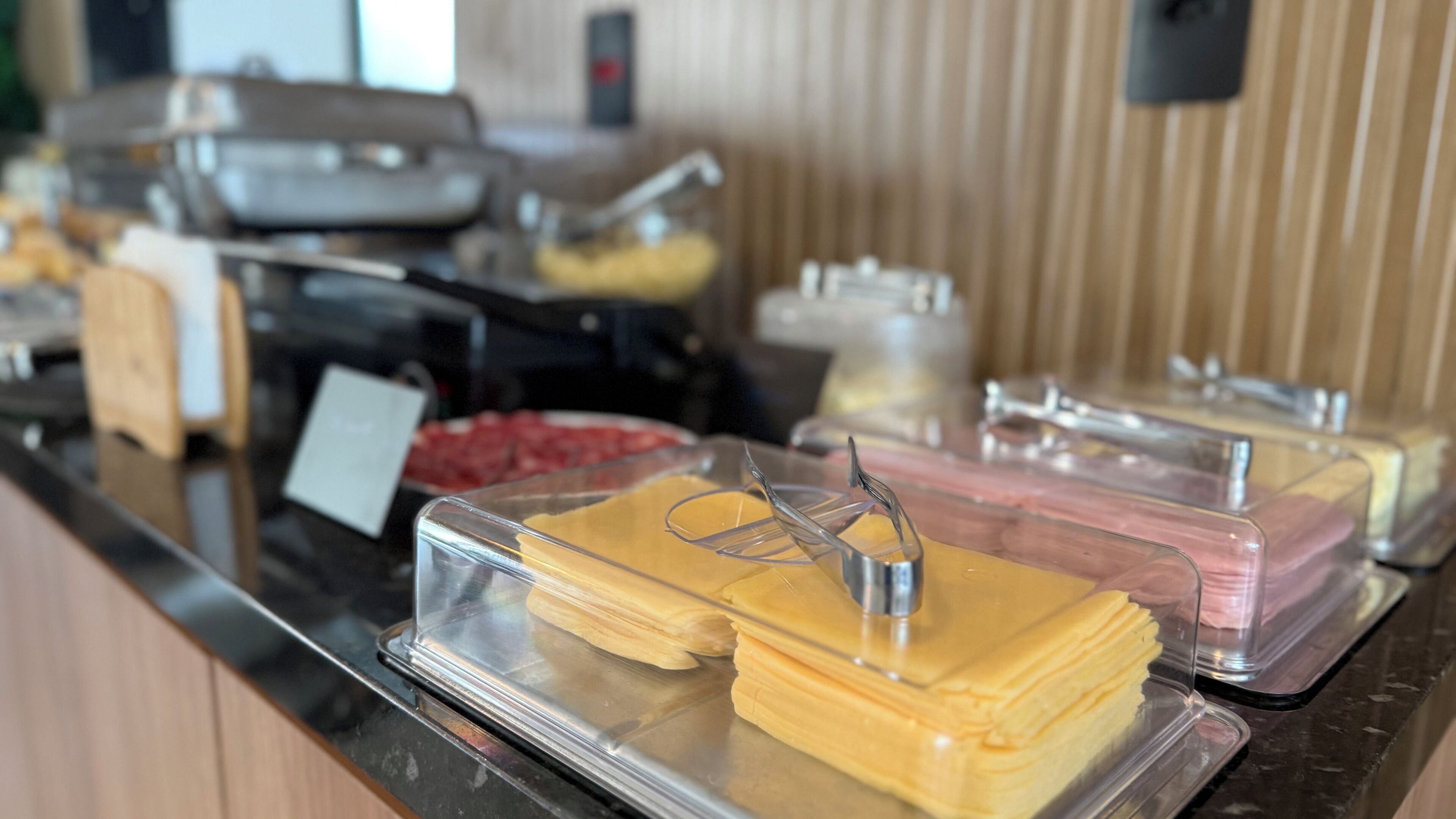 A buffet with various food items in clear containers, including what appears to be cheese and meat.