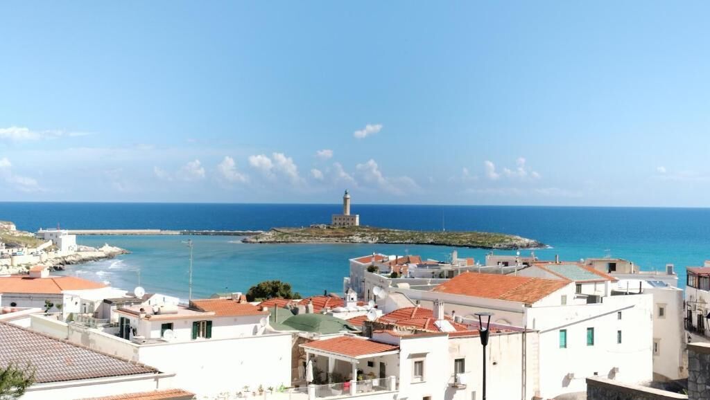 Une ville côtière qui se distingue par son phare imposant, ses bâtiments blancs aux toits recouverts de tuiles rouges et sa vue dégagée sur la mer.