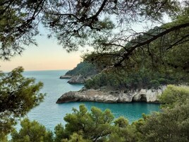Paesaggio costiero con scogliere rocciose e un mare blu limpido.