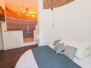 A modern bedroom with a bed, pillows, a shower area, and a hanging light fixture. - Rural Luxury Farmhouse | Hot Tub & Amazing Views, walks (Worcester)