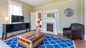 Un salon avec une cheminée, un téléviseur, une table basse et un fauteuil en cuir.