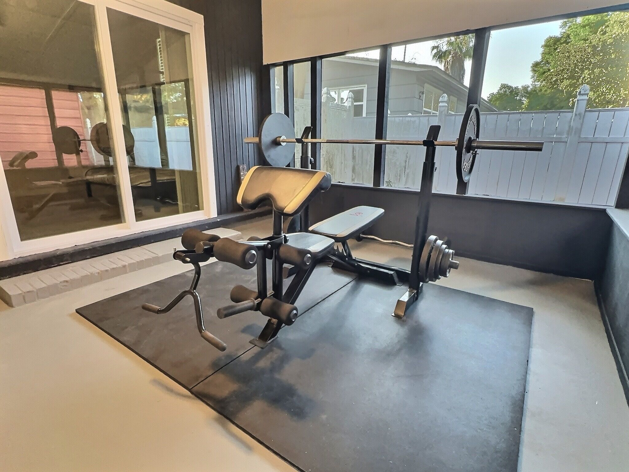 Ein Heimfitnessraum mit einer Hantelbank, einem Squat-Gestell und einer Gewichtbank.