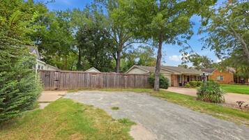 A residential area with a fenced backyard, a driveway, and houses with brick exteriors.