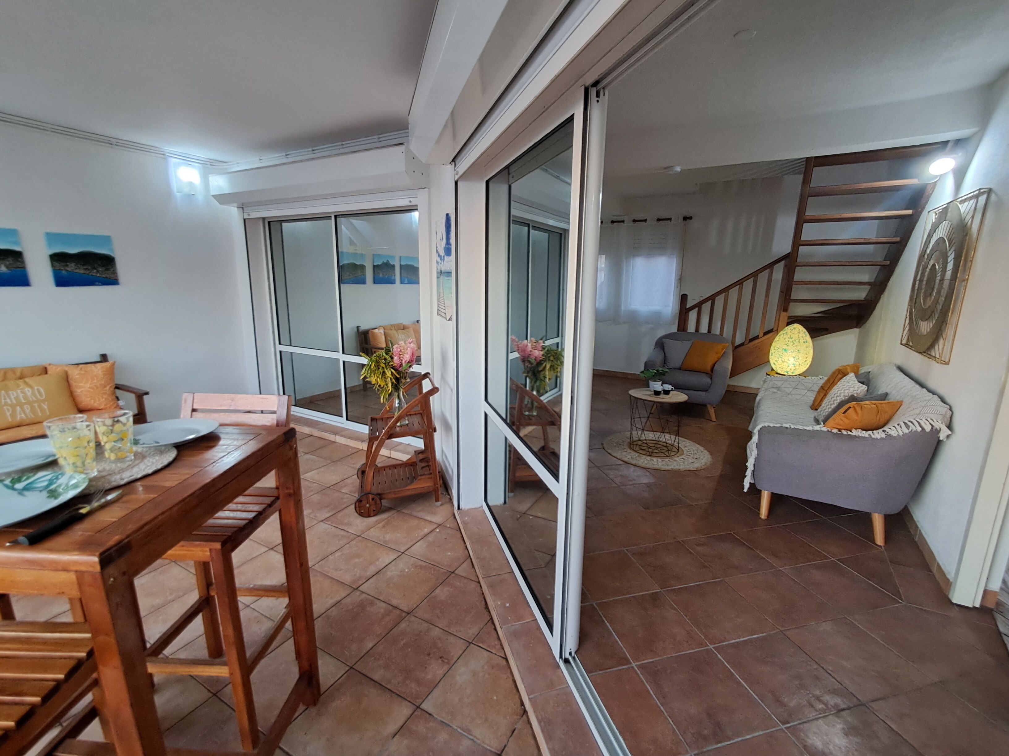 Un espace repas comprenant une table et des chaises en bois, un canapé et un escalier menant à un niveau supérieur.