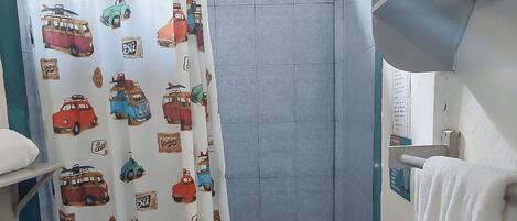A bathroom with a toilet, sink, and shower curtain featuring vintage car prints.