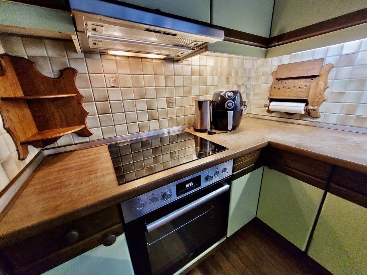 Una cocina con campana extractora de acero inoxidable, un tostador y una tabla de cortar de madera.