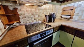 Una cocina con campana extractora de acero inoxidable, un tostador y una tabla de cortar de madera.