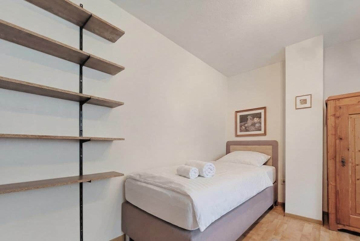 Une chambre à coucher avec un lit, une porte en bois et une étagère fixée au mur.