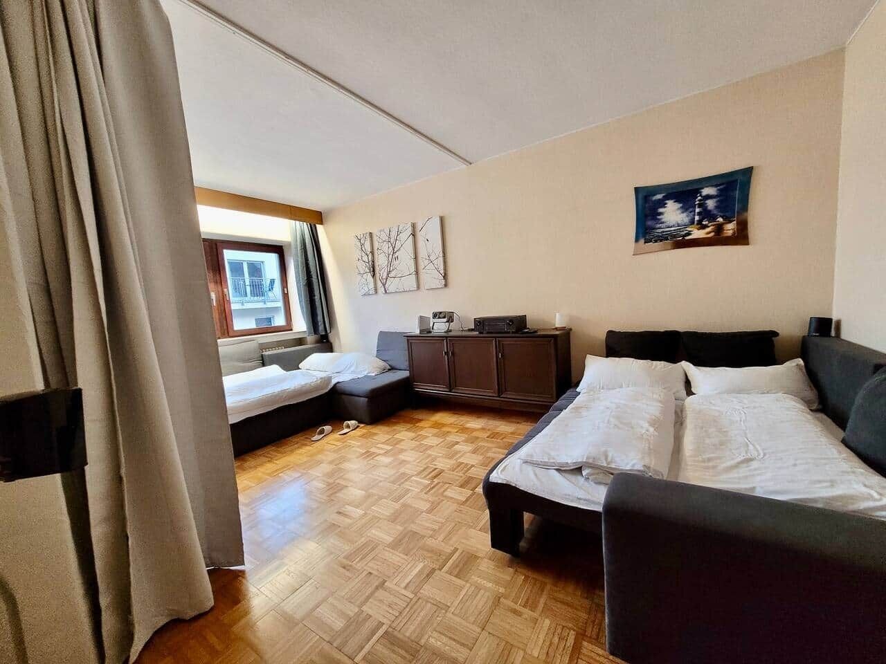 A hotel room with a bed, a sofa, a desk, and a window.