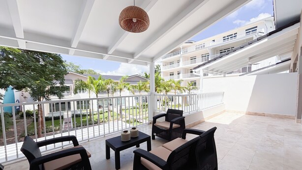 A covered outdoor area with wicker furniture and a hanging light fixture. - Tropical Voyage 3BR Garden View (Rio Hato, Coclé)