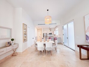 Een moderne keuken met witte kastjes, een roestvrijstalen koelkast en een eethoek met een witte tafel en stoelen.