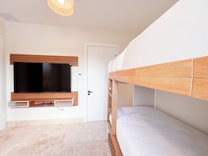 A bedroom with a bunk bed, a television mounted on the wall, and a door. - Tropical Voyage 3BR Garden View (Rio Hato, Coclé)