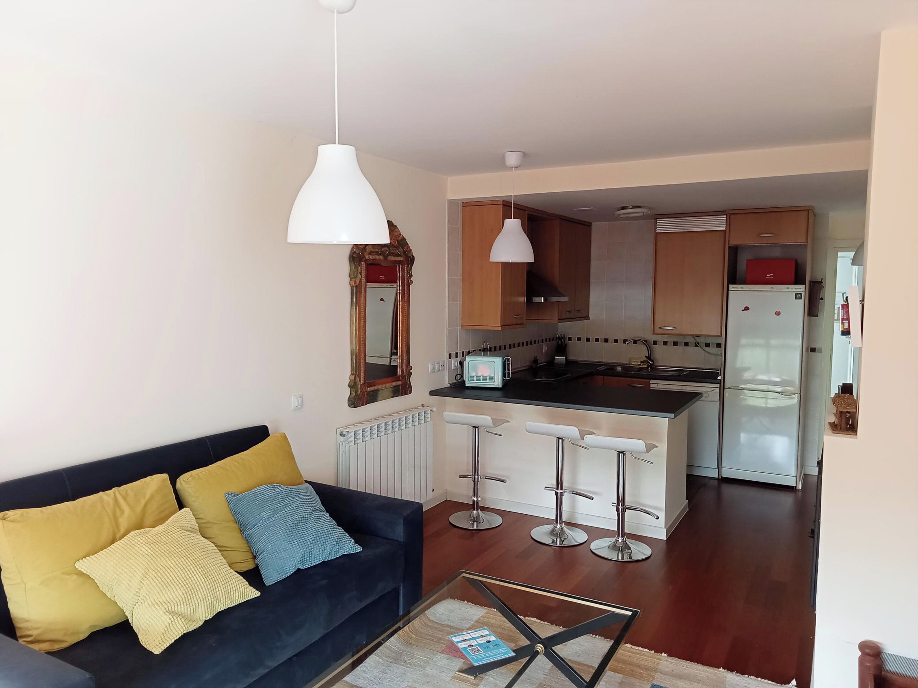 A modern kitchen with a central island, bar stools, and a dining area.