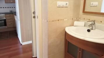 A bathroom with a sink, mirror, and wooden cabinet.