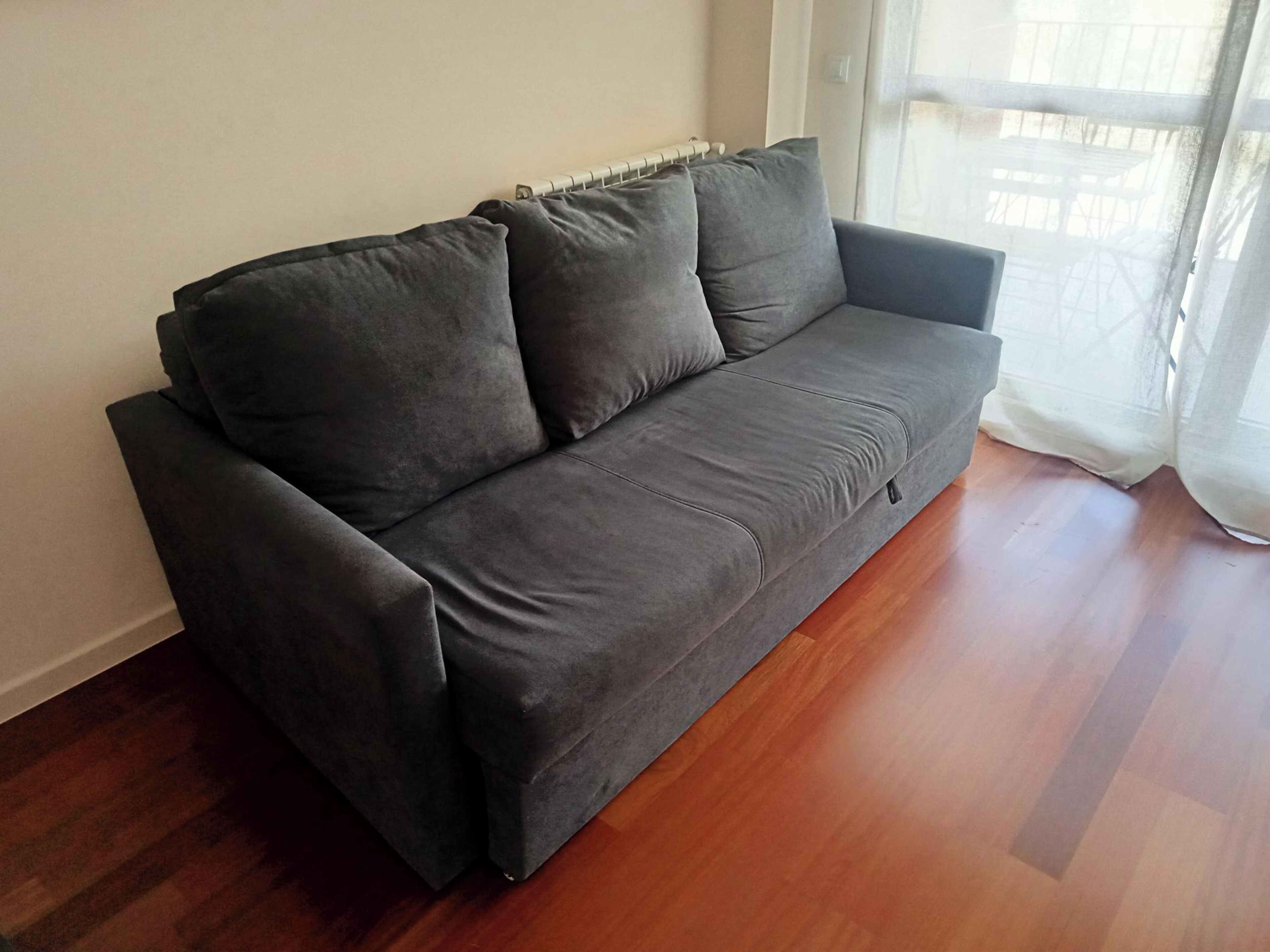 A grey sofa in a room with wooden flooring and a radiator.