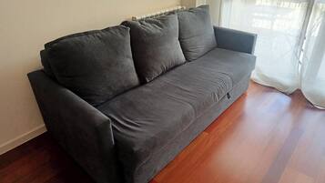 A grey sofa in a room with wooden flooring and a radiator.