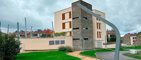Un edificio moderno con un diseño arquitectónico único, que presenta una combinación de paredes de ladrillo y enlucido, y una estructura metálica curva en primer plano.