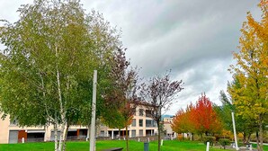 A park with benches, trees, and a building in the background. - Apartamentos Las Margas Sabiñanigo 3000 (Sabiñánigo)