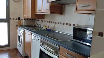 A kitchen with wooden cabinets, a stainless steel sink, a microwave, and a built-in oven.