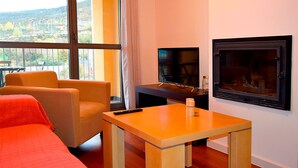 A modern living room with a sofa, a small table, a TV, and a fireplace. - Apartamentos Las Margas Sabiñanigo 3000 (Sabiñánigo)