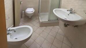 A bathroom with two sinks, a toilet, a shower enclosure, and a mirror. - Rifugio TEA Dolomiti (Canale d'Agordo)