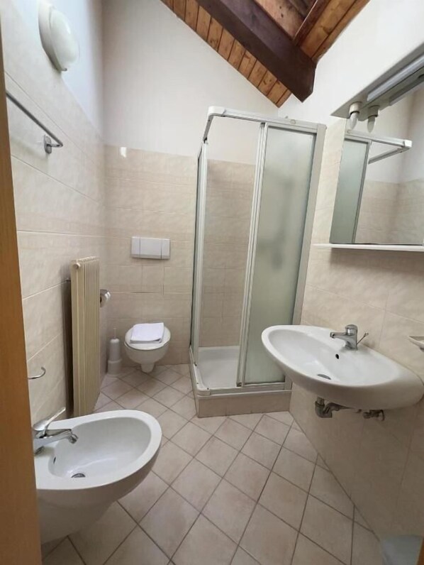 Une salle de bain avec deux lavabos, des toilettes, un espace douche et un miroir.